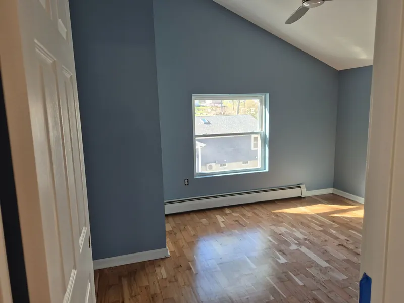 Bedroom painted in soft blue over hardwood floors